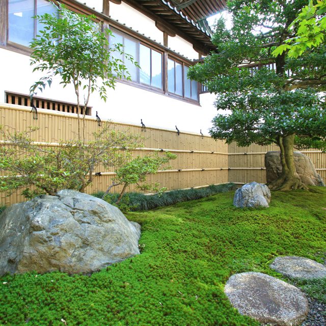 庭石がバランスよく配置された美しい和風庭園の背景に